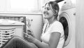 Black and white portrait of smiling housewife listening music with earphones at laundry room Royalty Free Stock Photo