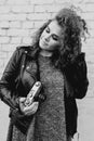 Monochrome portrait of young beautiful cheerful woman with curly hair on white bricks wall background. Royalty Free Stock Photo