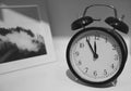 Monochrome Retro Alarm Clock on a Table with Blurrt Picture Frame in the Backdrop Royalty Free Stock Photo