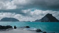 Monochrome Scene with Man Sitting by the Blue Sea and Mountains. Generative AI Royalty Free Stock Photo