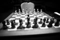 Monochrome shallow depth of field selective focus image with wooden chess pieces on a wooden table before a professional