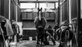 Monochrome shot of a horse being saddled by a man in a barn