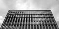 Monochrome shot of a modern college building surounded by clouds