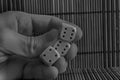 Monochrome Stack of three plastic dices in man`s hand on wooden table background. Six sides cube with black dots. Number 4, 6, 6.