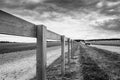 Monochrome view of wooden fencing seen next to a racecourse track in Newmarket.