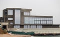 Monolithic concrete building under construction with panoramic glazing right on the seashore near the water line