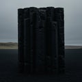 A monolithic structure of dark, volcanic basalt columns stands against a desolate Royalty Free Stock Photo