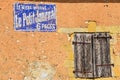 Old weathered wall with advertising and closed shutters in Dordogne