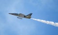 An L-39 Albatros jet flying against a deep blue sky with contrail