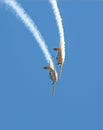 Two aerobatic aircraft perform a deep dive in a blue sky