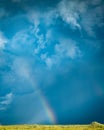 Monsoon storm rainbow in blue cloudy sky.