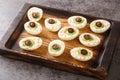 Monster eyes deviled eggs with a avocado and olives for Halloween day on a wooden tray. Horizontal
