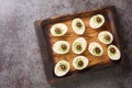 Monster eyes deviled eggs with a avocado and olives for Halloween day on a wooden tray. Horizontal top view
