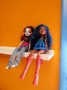 Monster Tall dolls sitting on white shelf against orange painted wall