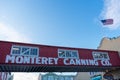 Monterey Canning Company sign on elevated bridge at Cannery Row. Flag of the United States in blue sky - Monterey, California, USA