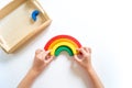 Montessori wood rainbow material. A child plays with a toy with his hands