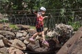 Montestrutto, Italian alps - June 2020: a girl walks along a Tibetan bridge rope-smeared cliff in an adventure park