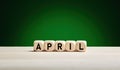 The month April written on wooden cubes against green spring background with copy space. Month of the year