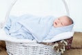 0-1 month Asian newborn baby lie down on basket, baby sleep in white basket wrap up by soft blanket, mother or woman hold the Royalty Free Stock Photo