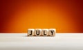 The month July written on wooden cubes against summer background with copy space. Month of the year