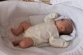 1 month old baby girl in beige bodysuit sleeps in her white cradle Royalty Free Stock Photo