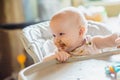 6 month Old Baby Girl At Home In High Chair eating tasty food at home. Funny baby with soiled healthy broccoli puree face having Royalty Free Stock Photo