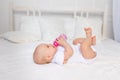 A 6-month-old baby lies on a white bed and drinks milk from a bottle, baby food concept, text space