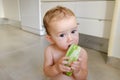 10-month-old baby sitting on the floor of her kitchen nibbling a slice of watermelon getting dirty all over