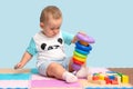 A 15-23-month-old baby sitting playing with a pyramid bath made of colorful plastic rings Royalty Free Stock Photo