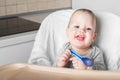 11 month old baby with spoon on high chair. First baby food, pureed food, baby-led weaning, BLW Royalty Free Stock Photo