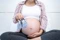 A 8 month pregnant woman is happy to prepare shoes for baby. Good mother or mom