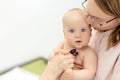 Monther holding baby on hands at doctors office. Pediatrician making examination of little cute infant boy with Royalty Free Stock Photo