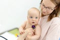 Monther holding baby on hands at doctors office. Pediatrician making examination of little cute infant boy with Royalty Free Stock Photo