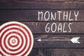 Monthly goals concept with dart board on dark wooden wall