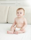 Adorable 10 months old baby boy in diapers sitting on bed Royalty Free Stock Photo