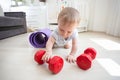 Cute 9 months old baby boy holding big red dumbbells. COncept of children in sport Royalty Free Stock Photo