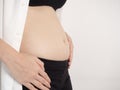 3 months pregnant Asian woman in white bed room, showing her ultrasound film. Woman touching her abdomen belly and looking at x-ra