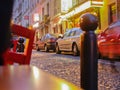 Montmartre street perspective of narrow cobbled surface with parked cars and illuminated signs