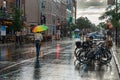 Woman on Mont-Royal Avenue holding rainbow umbrella during rain & storm