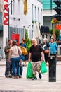 Canadian old man carrying plastic shopping bags on the crowded street