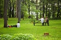 Two young couples sitting on the grass and bench in the forest and having a conversation in Mount Royal park, Montreal, Canada