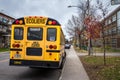 North American Yellow School Bus parked on a street, waiting for students with cars passing by Royalty Free Stock Photo