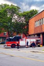 Montreal fire department building with parked fire trucks. Firefighters describing an address to a Canadian woman