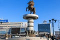 Monument of Alexander The Great in Skopje's main square with people passing by.