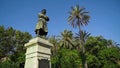 Monument of man on pedestal on background of green trees and sky. Action. Bottom view of beautiful statue of man on