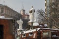 The monument of princess Olga wearing bulletproof west with rusty remains of destroyed russinan military warfare