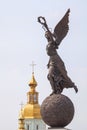 Monument to goddess Nike on sphere against cupolas of the church.