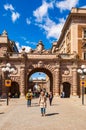 Monumental stone arch entrance to the area of cozy medieval streets and squares with attractions, walking people, interesting