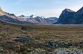 Monumental, wild arctic valley during sunset. Tall peaks with snow on top and river bed below. Duskfall at Akshayuk pass