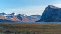 Monumental, wild arctic valley during sunset. Tall peaks with snow on top and river bed below. Duskfall at Akshayuk pass